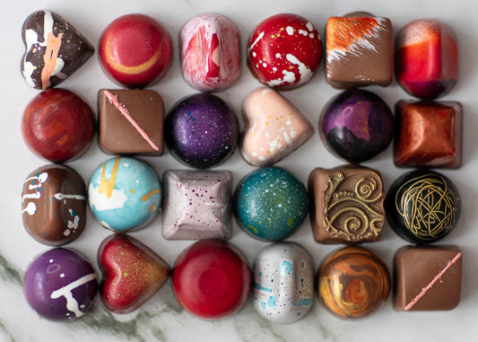 Artisan chocolates beautifully arranged on a wooden board, showcasing a variety of shapes and flavors.