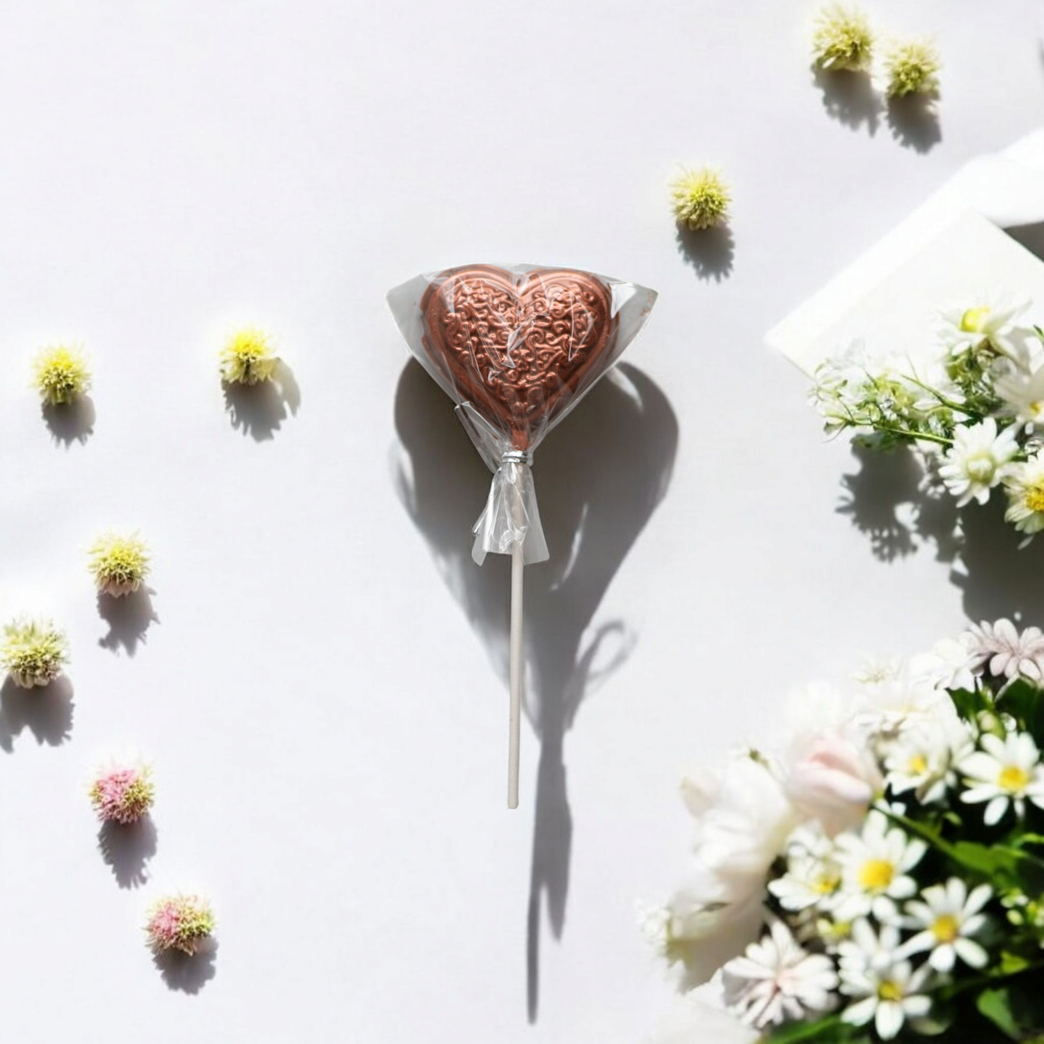 Heart-shaped chocolate lollipop on white background